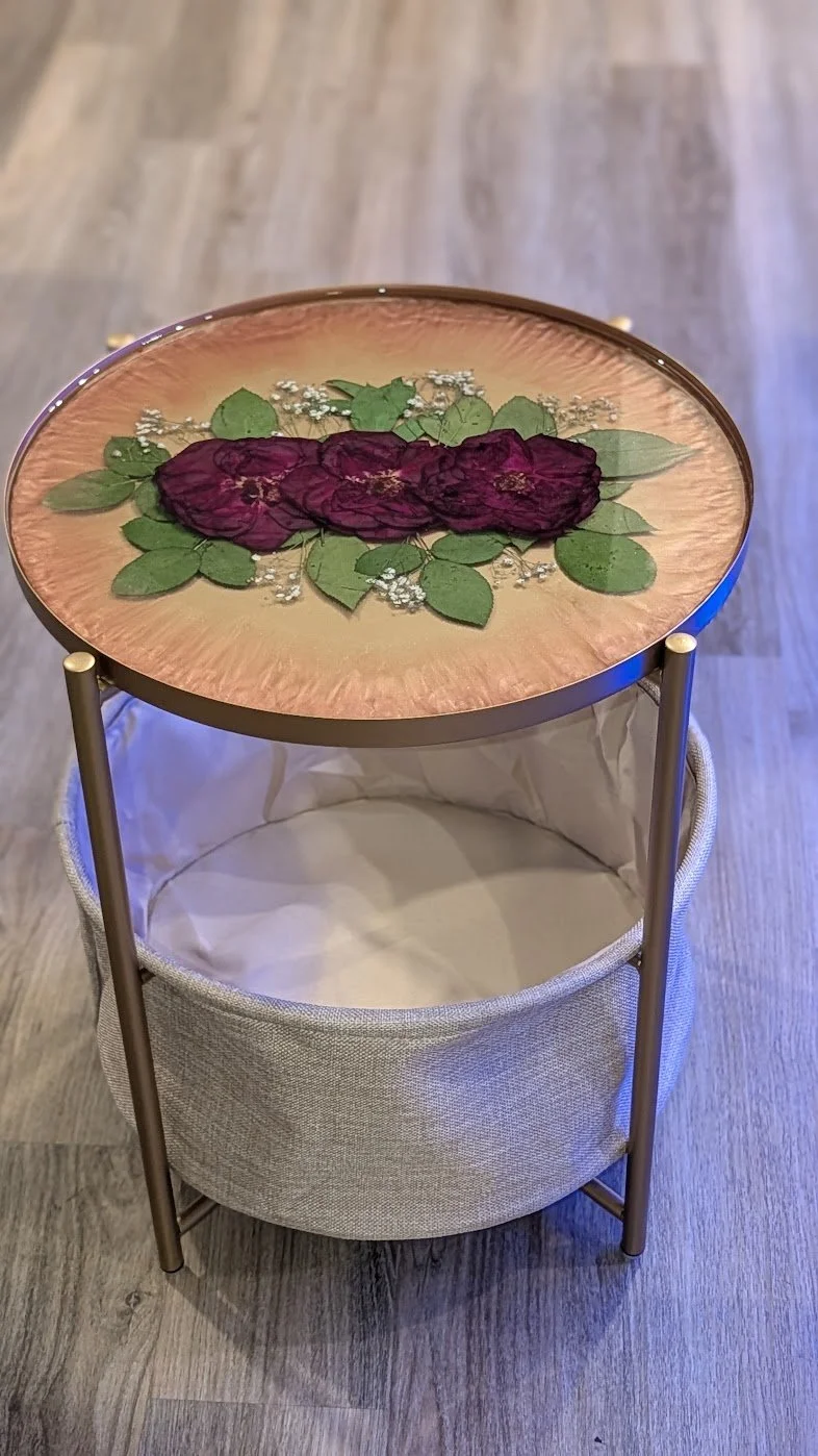 Full view of the floral resin side table and storage basket on a wood floor.