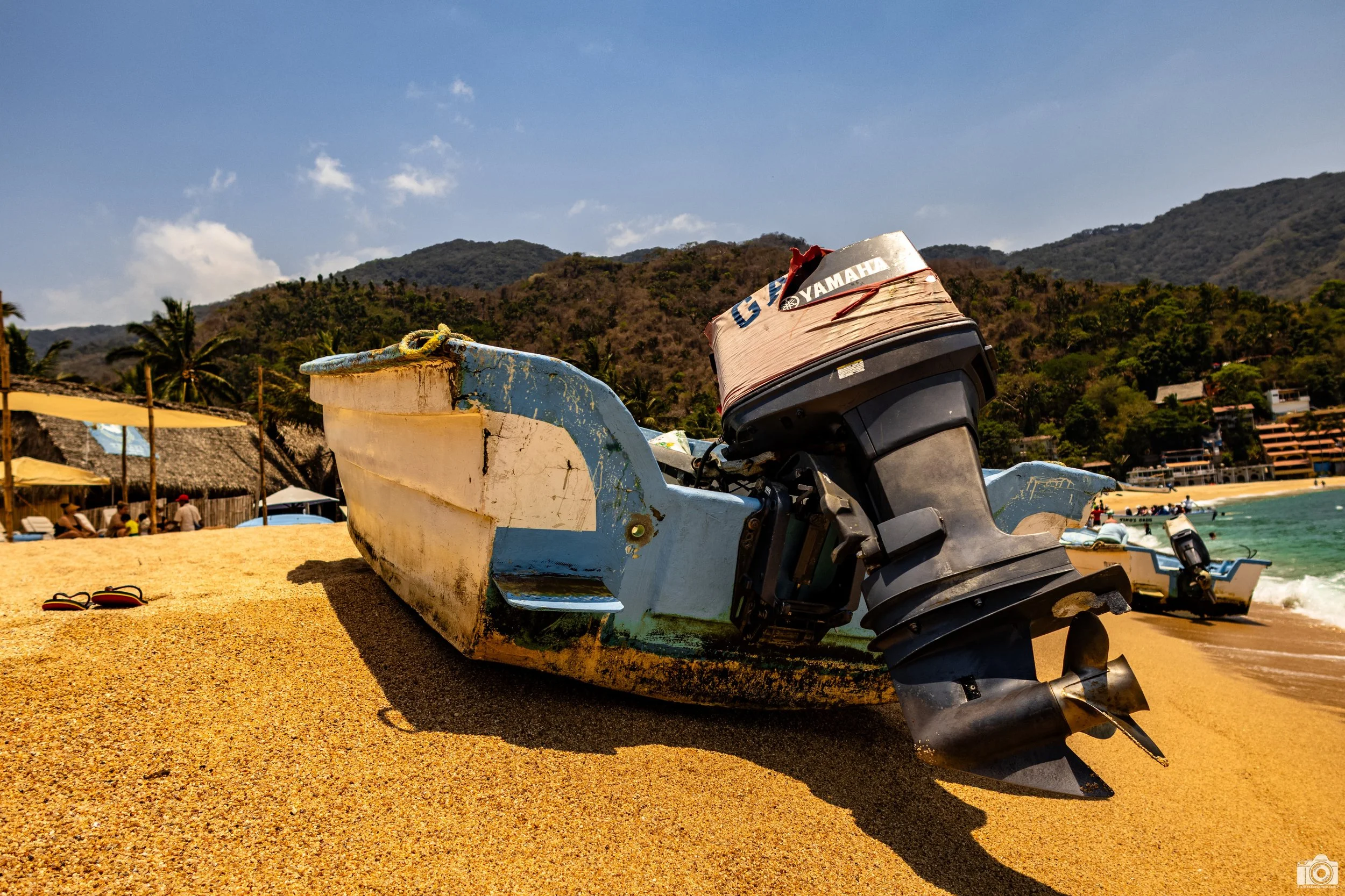 Yelapa, MX 2023.  The Commuter Boats.  I know this boat is not in the water, but at one time it was and one of these little motor boats tendered us to the shore from our tour vessel.  Those are my flip-flops in the sand.  Shot taken with a Canon EOS 