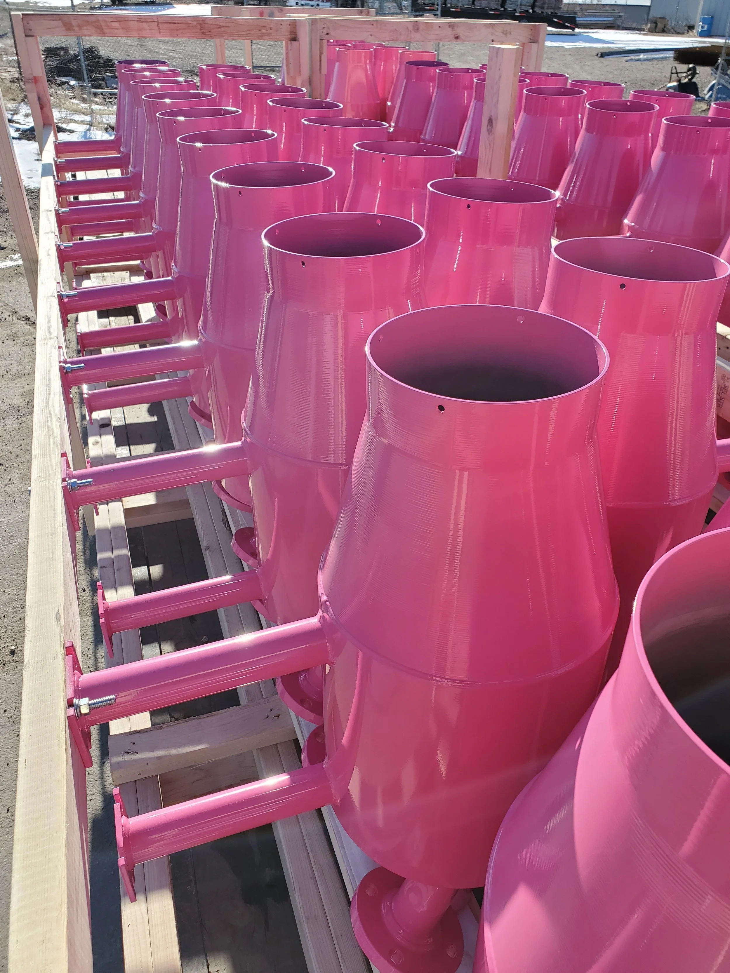 Multiple pink industrial exhaust vents lined up on a construction site.