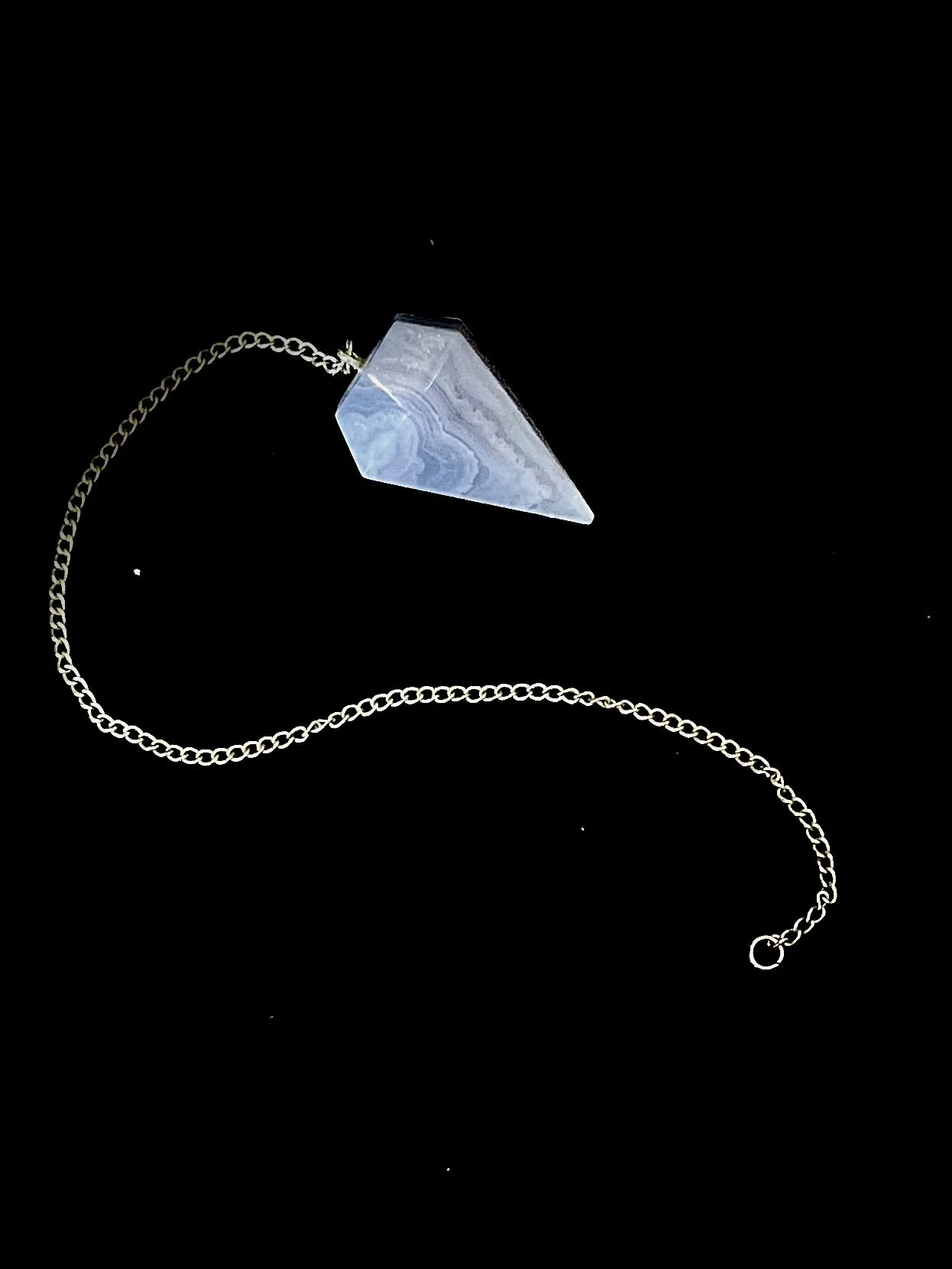 A necklace with a pointed, crystalline pendant on a silver chain, displayed against a black background.