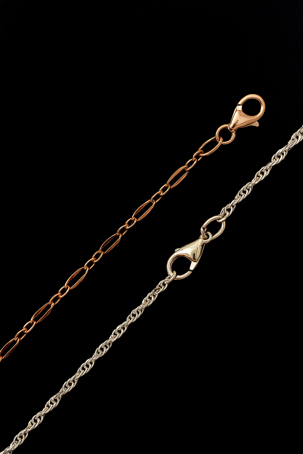 Two metal chains, one gold and one silver, with lobster clasp clasps, on a black background.