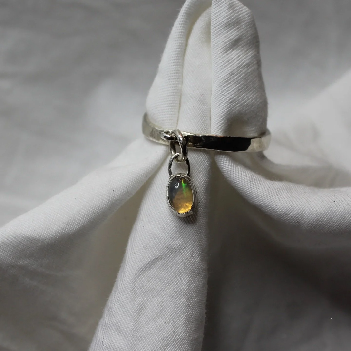 Ethiopian white opal with flashes of rainbows &amp; bright greens set in a charm style ring, perfect stacker piece &amp; a lovely little fidget toy 

available at mispoke.au #sterlingsilver #silver #jewellery #charm #opal