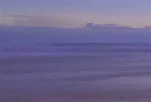 A serene scene of a calm body of water under a cloudy sky during twilight.