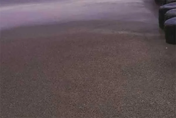 Empty asphalt parking lot with a few vehicles partially visible at the edges.