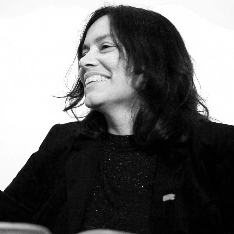 Black and white photo of a woman with shoulder-length dark hair, smiling and looking to her left.