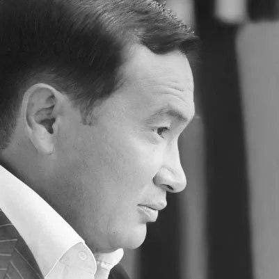 Close-up of a man in profile with a serious expression, wearing a pinstripe suit and white shirt