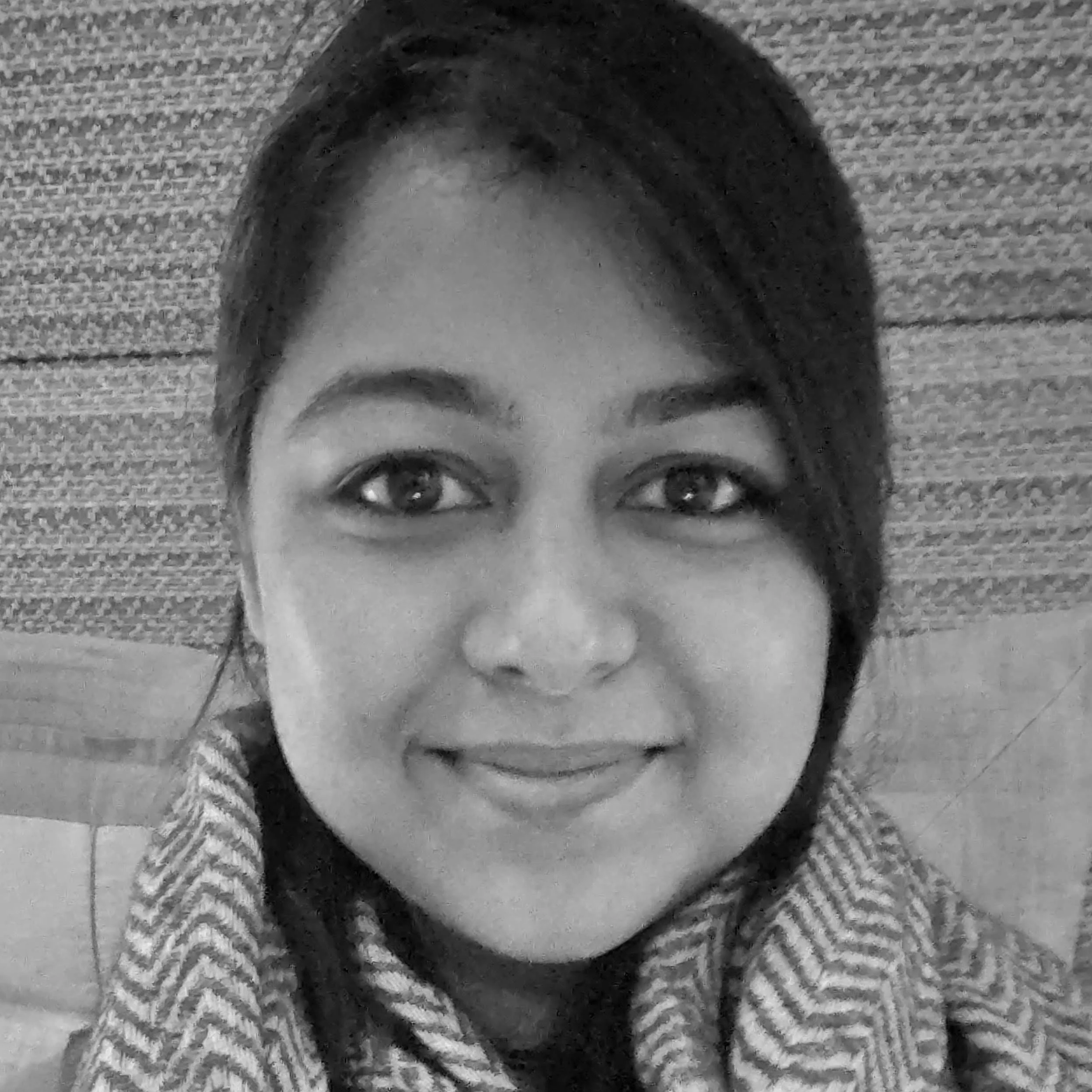 A smiling woman with long dark hair and light eyes, wearing a patterned scarf, in black and white.