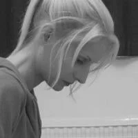 A young woman with long blonde hair looking downward in a black-and-white photo.