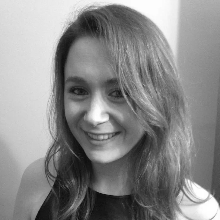 A young woman smiling with wavy hair in a black sleeveless top, black and white photo.