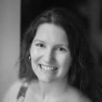 A smiling woman with shoulder-length hair and earrings, black and white photo