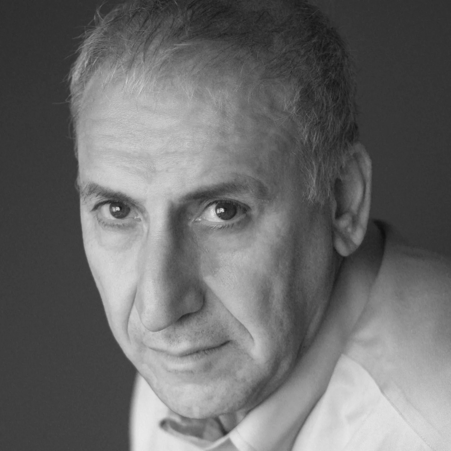 Black and white close-up portrait of a middle-aged man with short, light-colored hair and light eyes, looking directly at the camera with a serious expression.