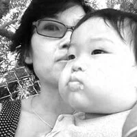 Black and white photo of a woman and a young child, with the woman giving the child a kiss on the cheek.