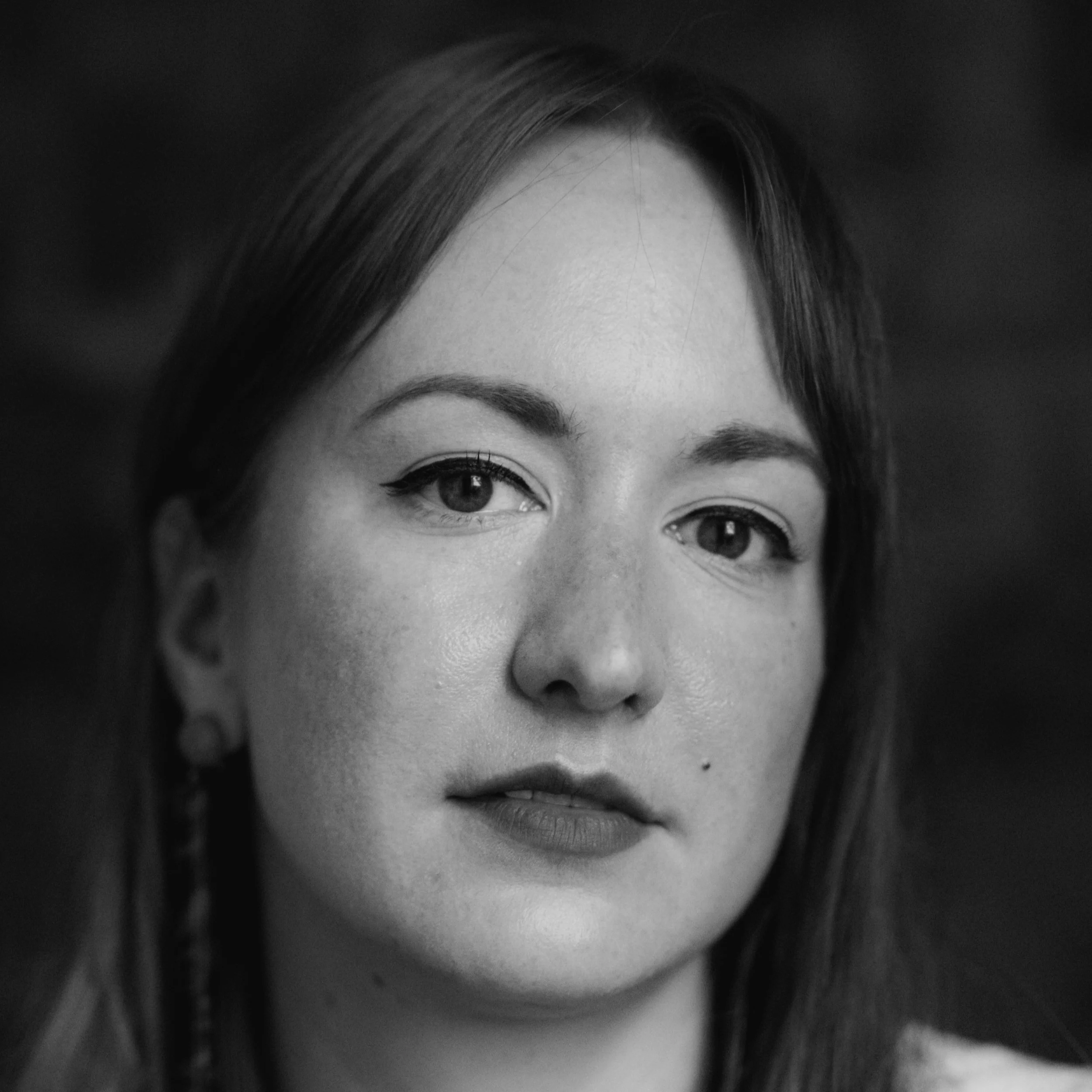 Close-up black and white portrait of a woman with straight hair and a subtle smile.