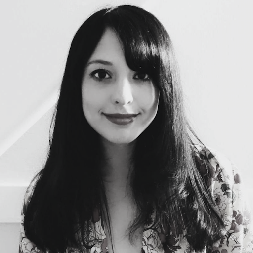 Black and white portrait of a woman with long dark hair, smiling, wearing a floral top.