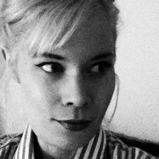 A black and white portrait of a woman with short hair, wearing a collared shirt, looking to the side.