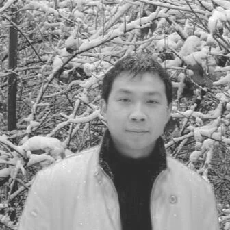 Portrait of a young man outdoors in a snowy landscape with snow-covered trees in the background.