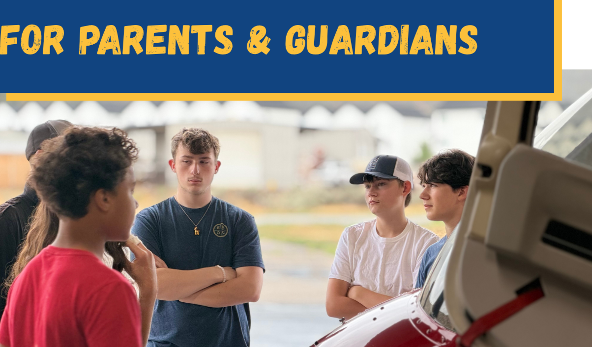Group of teenagers engaged in conversation outdoors, with a vehicle in the foreground and a sign above reading "For Parents & Guardians".