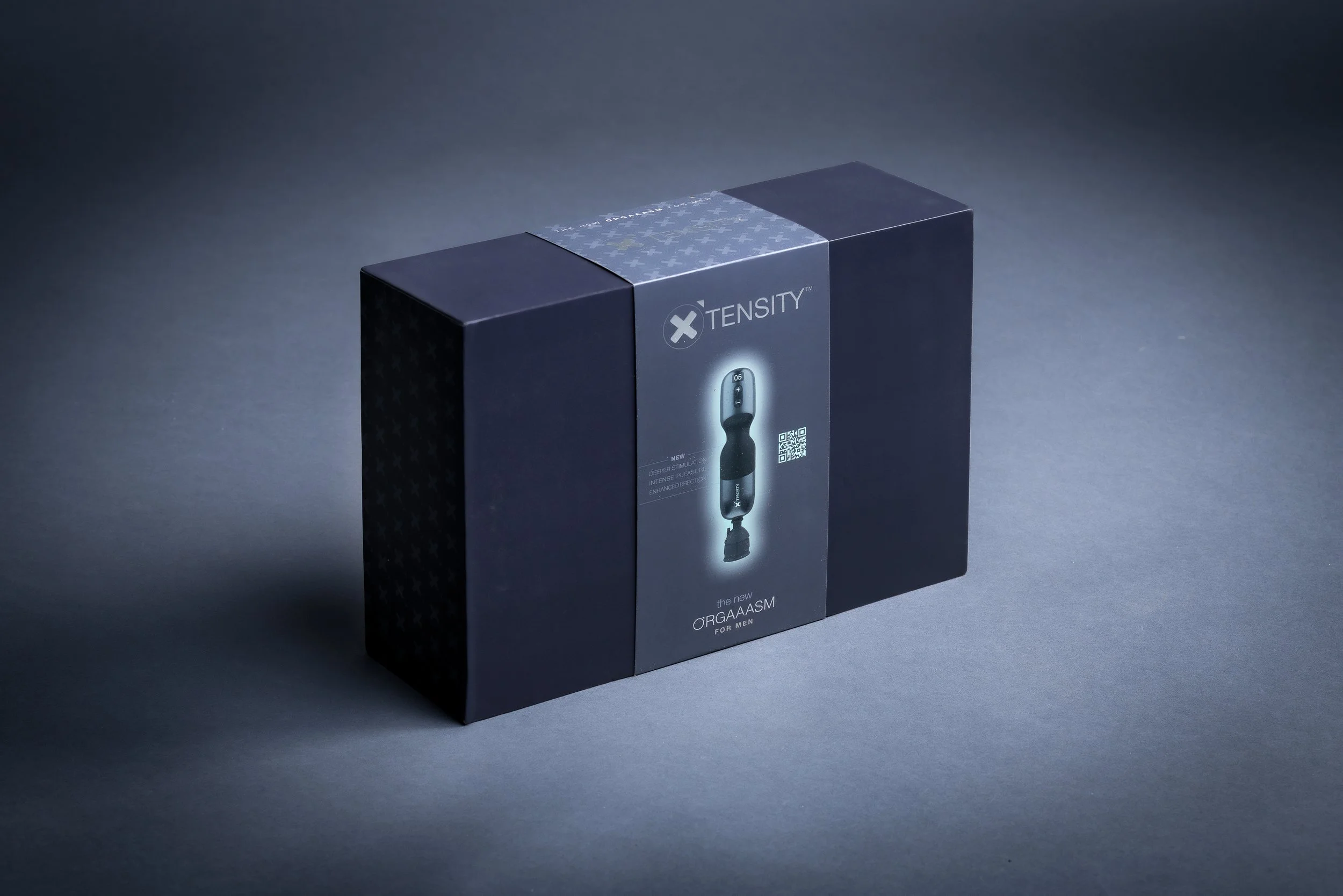 Box packaging for a XTENSITY Orogaaasm for men, dark blue with a central label showing the product image and a QR code.