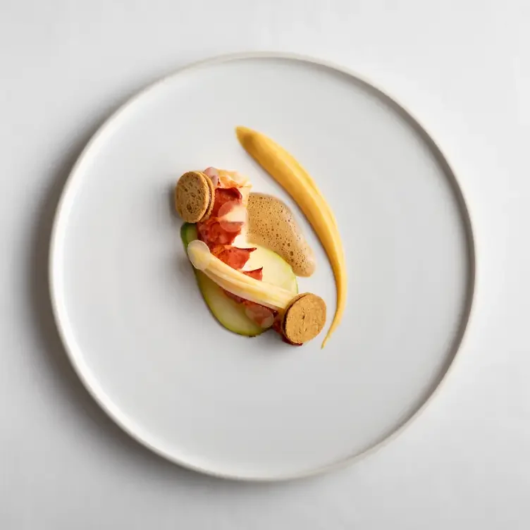 Elegant gourmet dish with seafood, sauce, and garnishes on a white plate