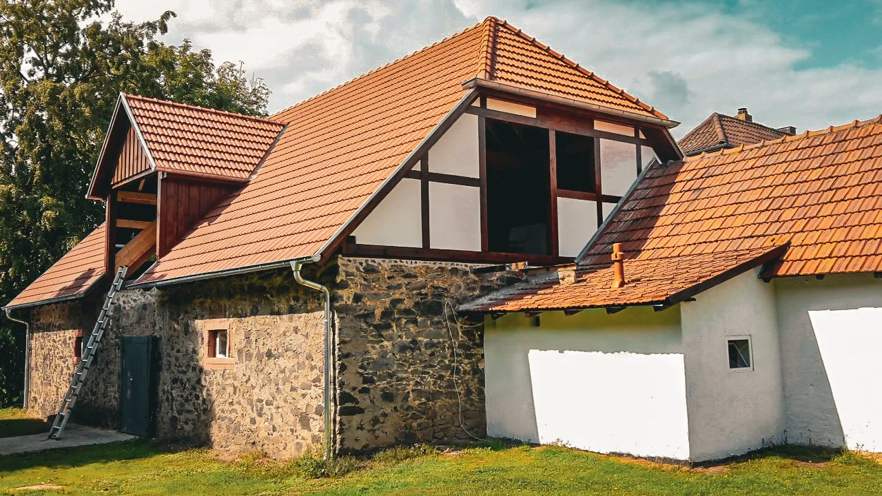 Ein Haus mit roten Ziegeldächern, teilweise mit Fachwerk und einer Steinmauer