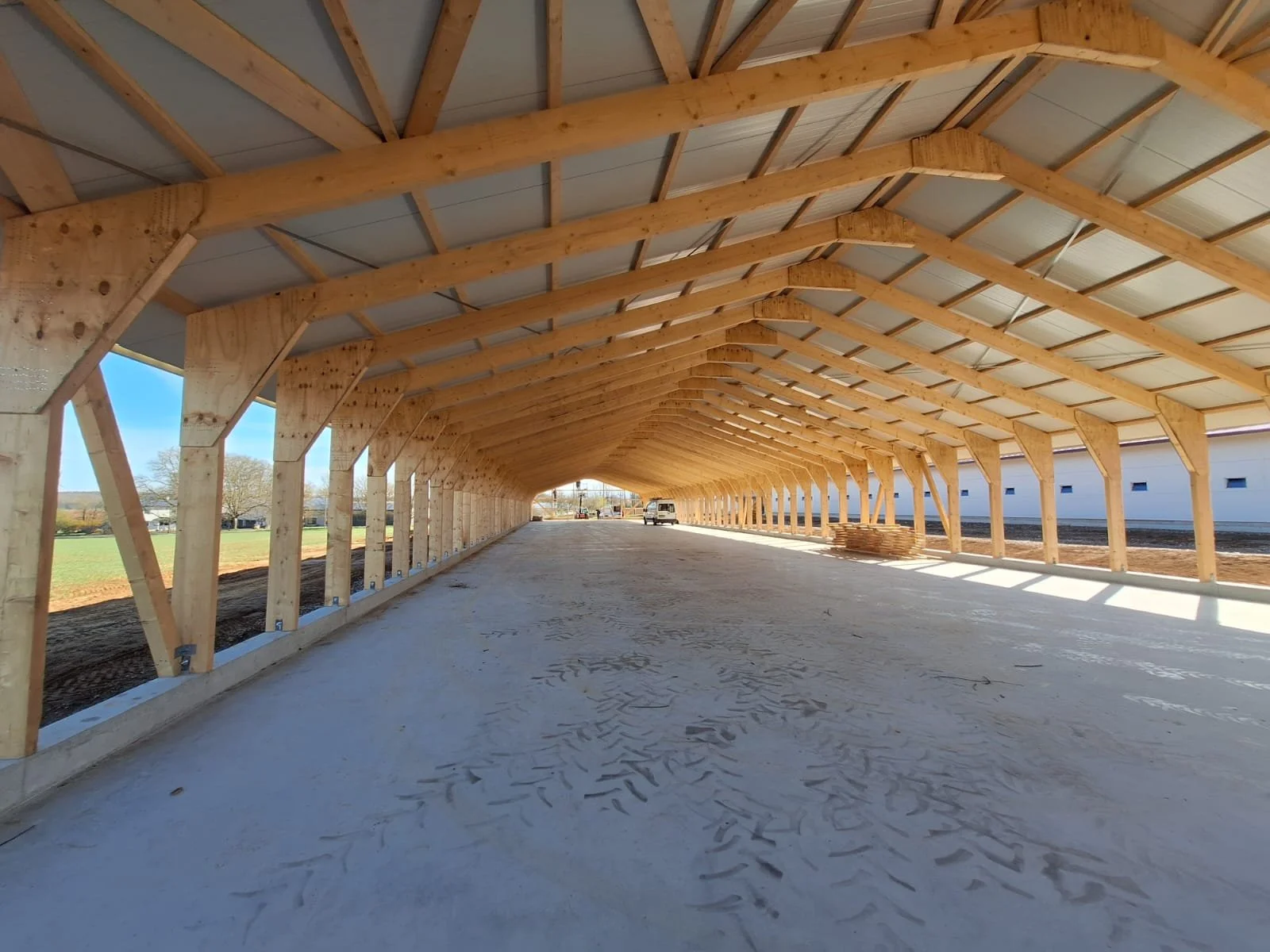 Ein Holzrohrgebäude im Bau, mit sichtbaren Holzbalken und einem unbefestigten Boden im Innenraum.