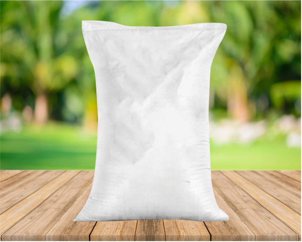 A white bag or sack standing upright on a wooden surface outdoors with green foliage in the background.