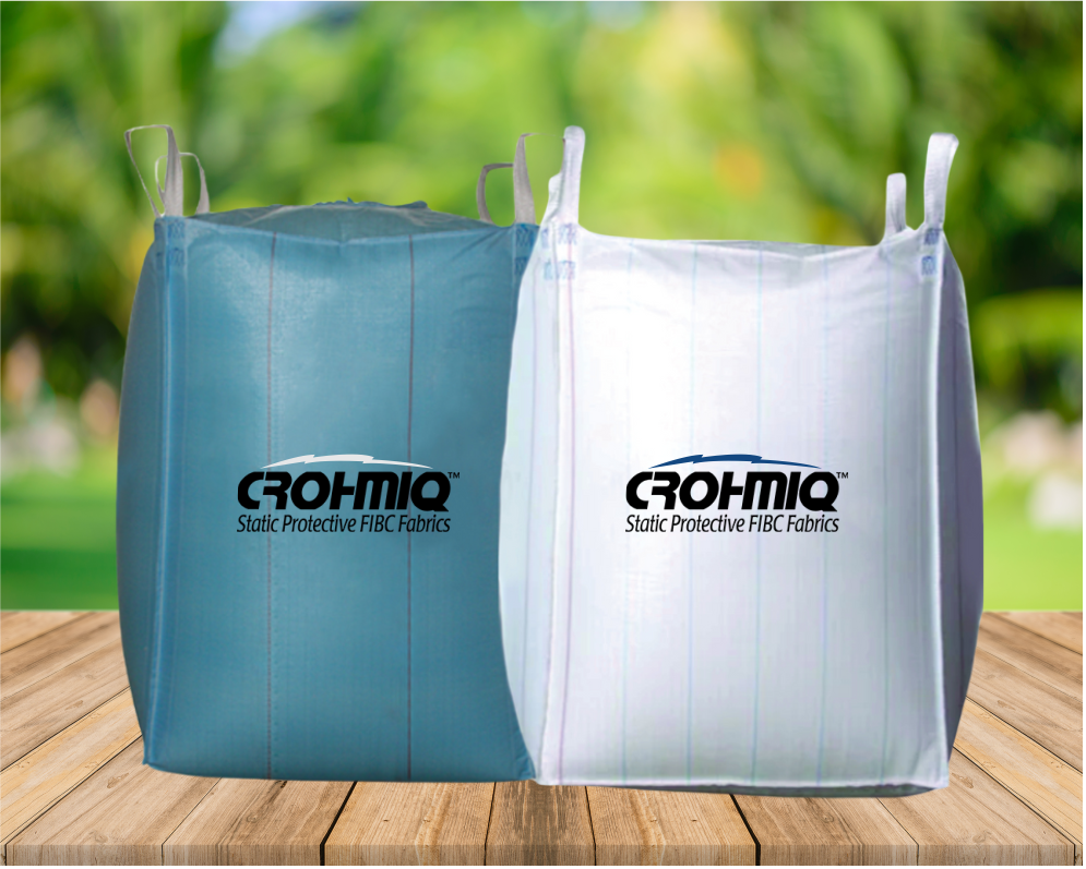 Two large bags of protective FIBC fabrics on a wooden surface, outdoors with a blurred green background.
