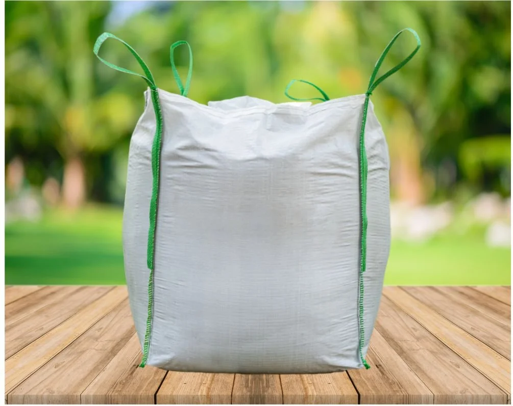White recyclable bag with EcoSafe logo on a wooden surface, outdoors with blurred green trees in the background.