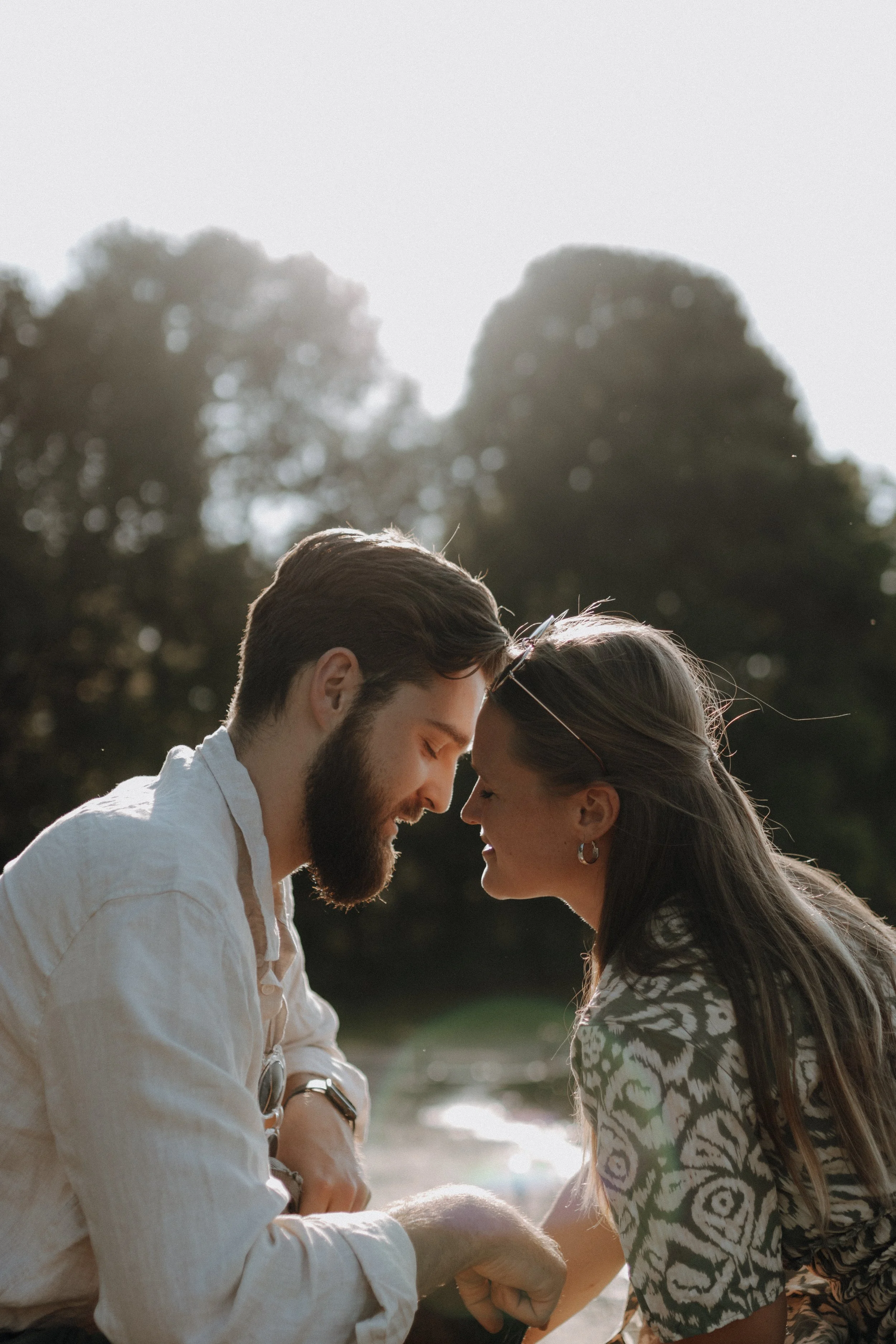 Ein lachendes Paar, das sich an der Nase berührt, im Freien bei Sonnenuntergang.