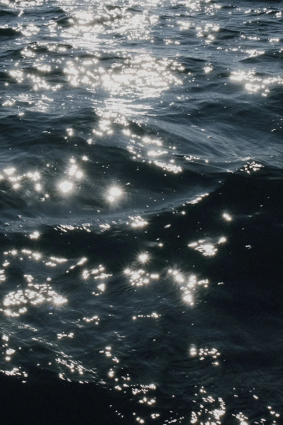 Glänzende Wasseroberfläche mit Sonnenreflexionen auf der Meeres- oder Seenebene.