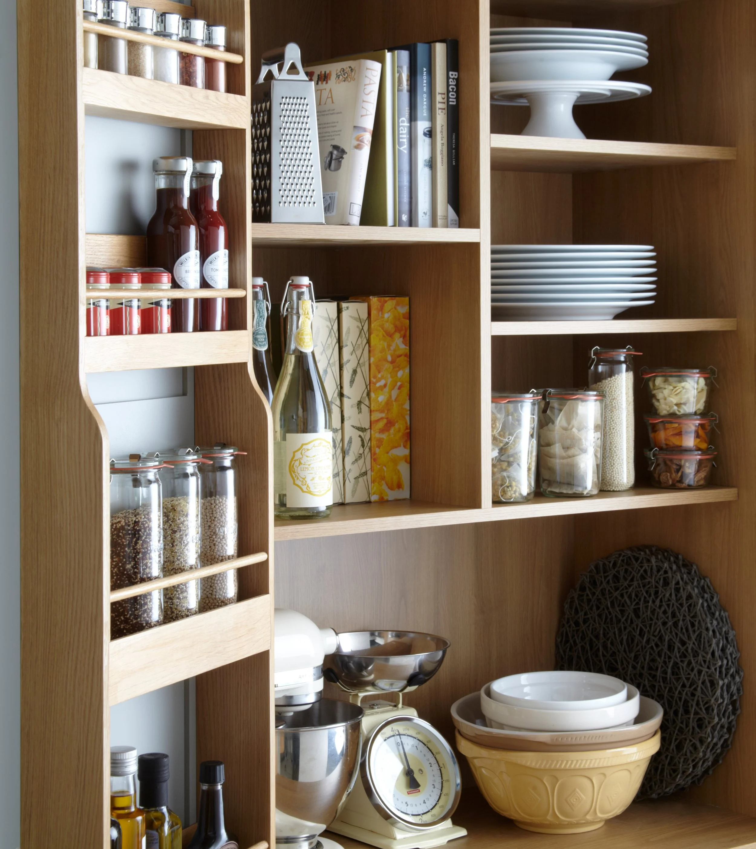 Bespoke oak larder storage in a North London kitchen, featuring open shelves, spice jars, dinnerware and beautifully crafted cabinetry