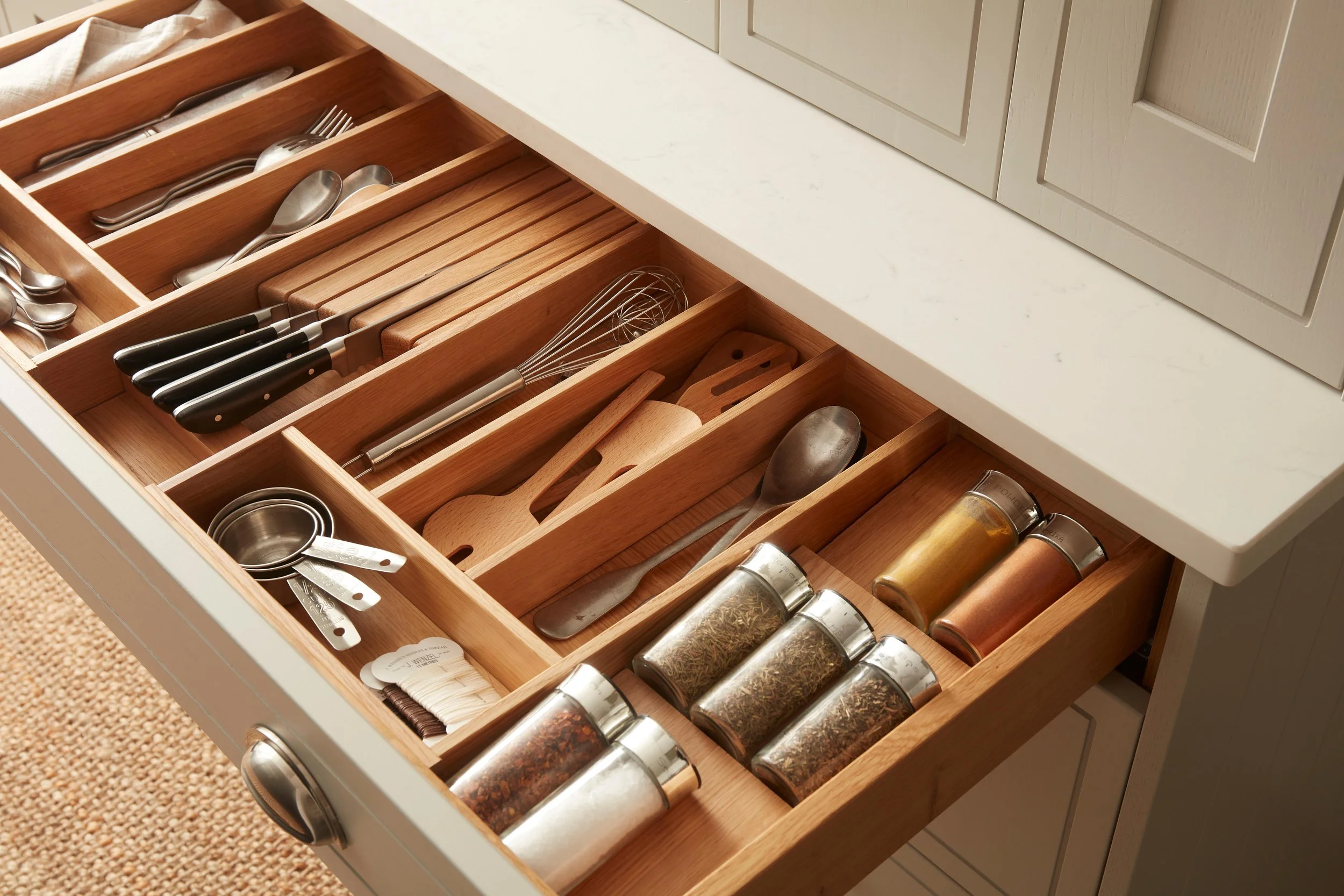 Made-to-measure kitchen storage in a North London home, featuring a bespoke oak drawer organiser for utensils, knives and spices.