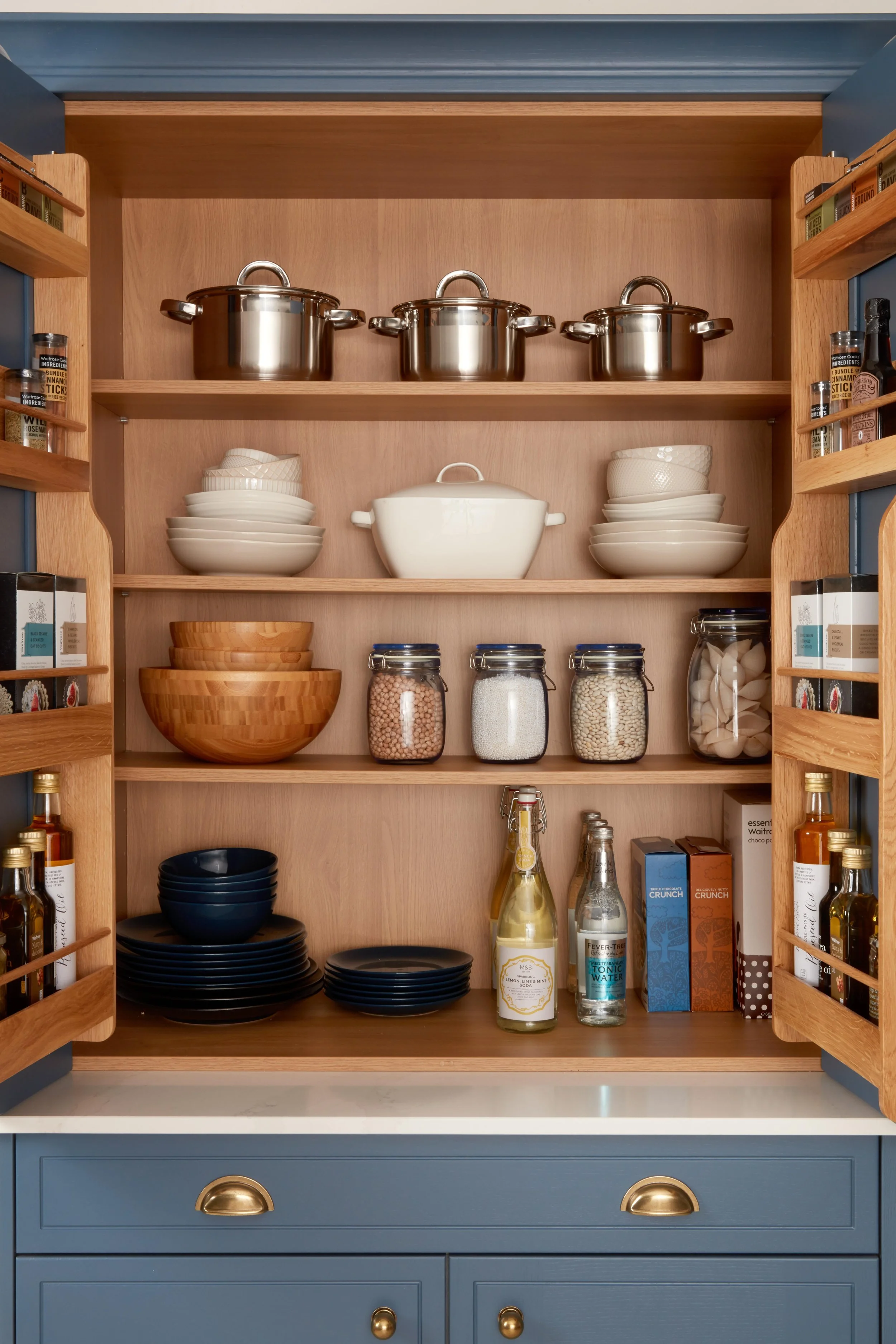 Beautifully organised oak larder cupboard in a bespoke North London kitchen, featuring cookware, dinnerware and pantry jars for premium storage