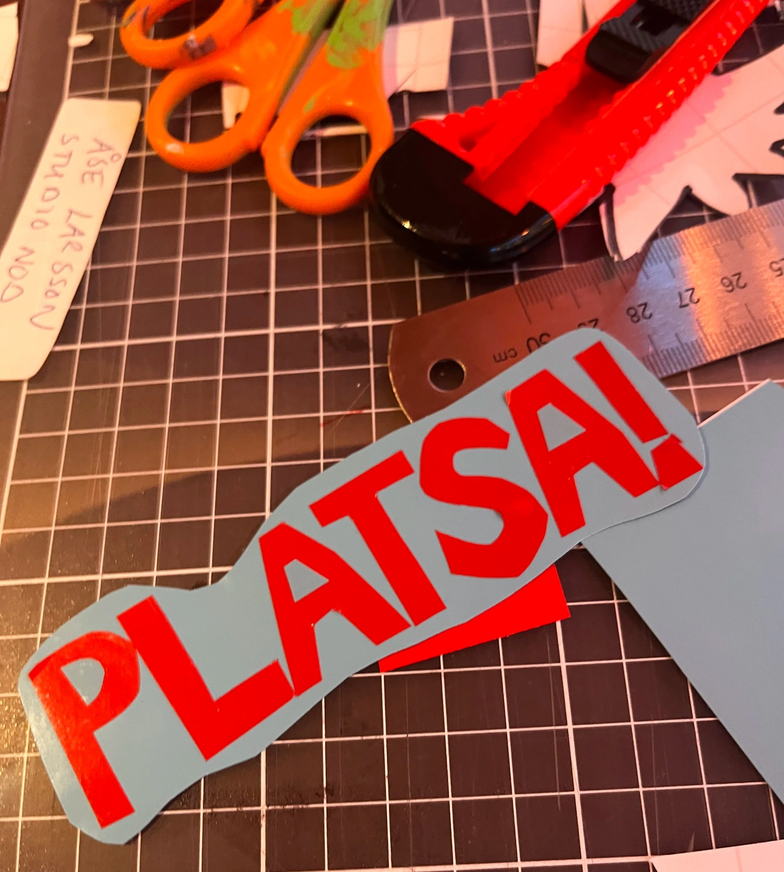 Bild på en sidoruta av en skylt eller stickers med rött och vitt STÄNGT i stora bokstäver, en linjal, en knapp, ett par saxar och några lappar med text. Det finns även en black gridbakgrund.