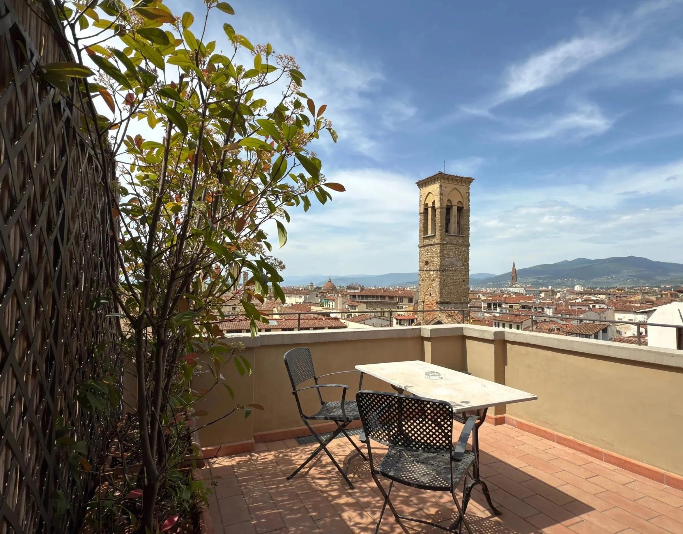 Private balcony at Antica Torre Tornabuoni, Florence – terracotta terrace with greenery, panoramic views of Duomo, Torre di Arnolfo, Arno River, and Tuscan hills. Luxury Italian stay