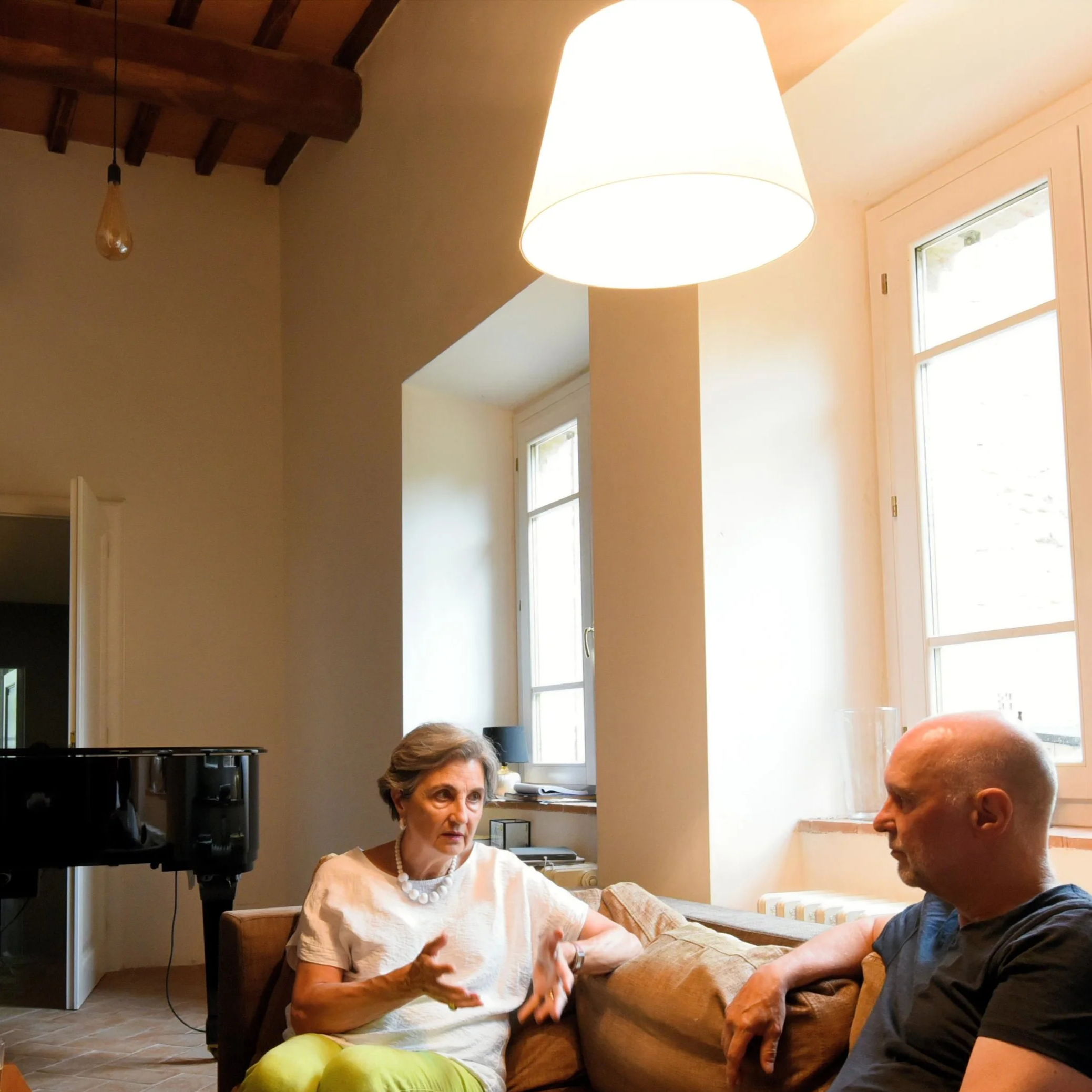 Elvira Lato speaking with a man in a bright Umbrian living room.