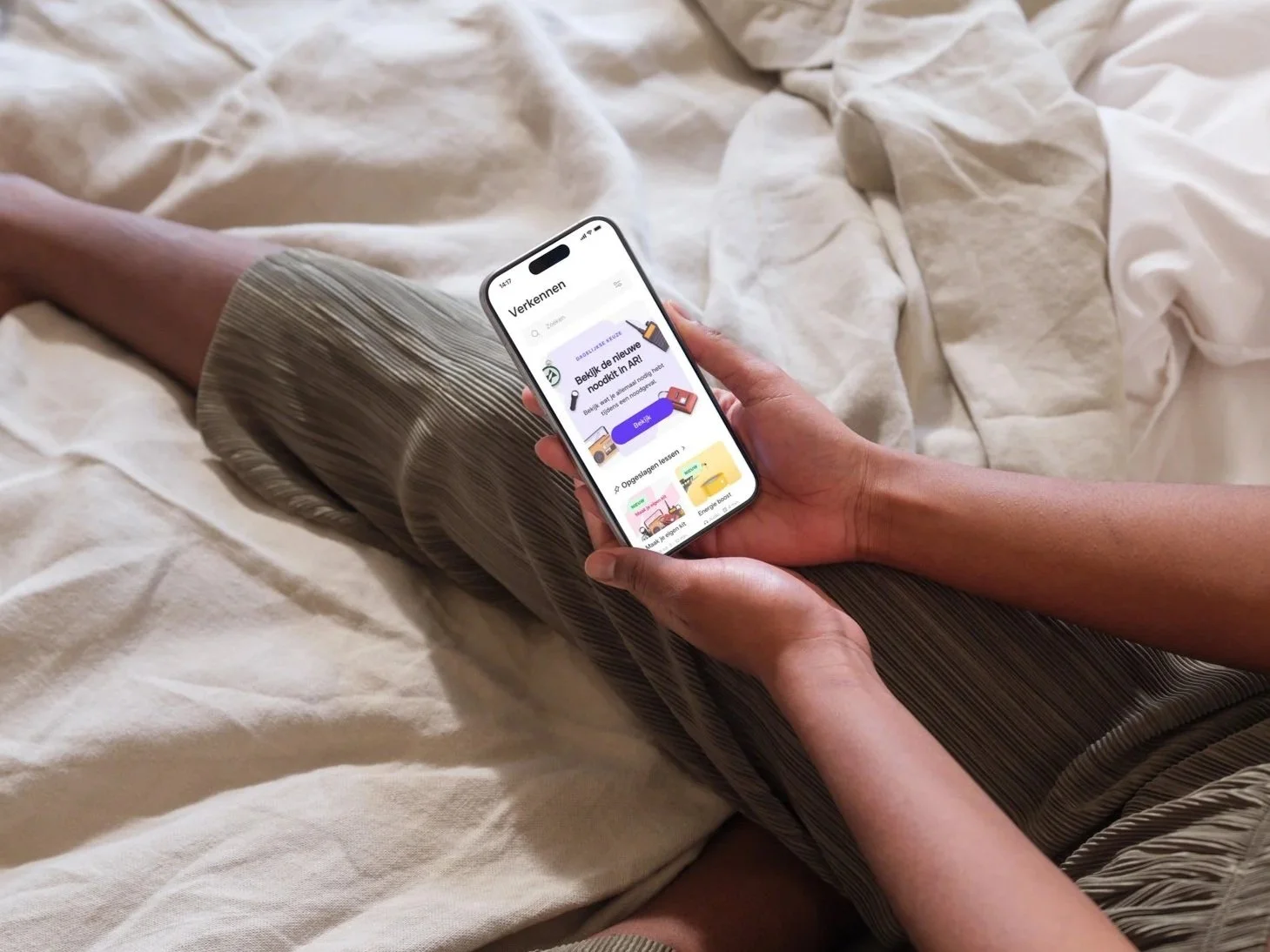 Persoon ligt op bed en gebruikt een smartphone met een app voor het verkennen van nieuwe boeken.