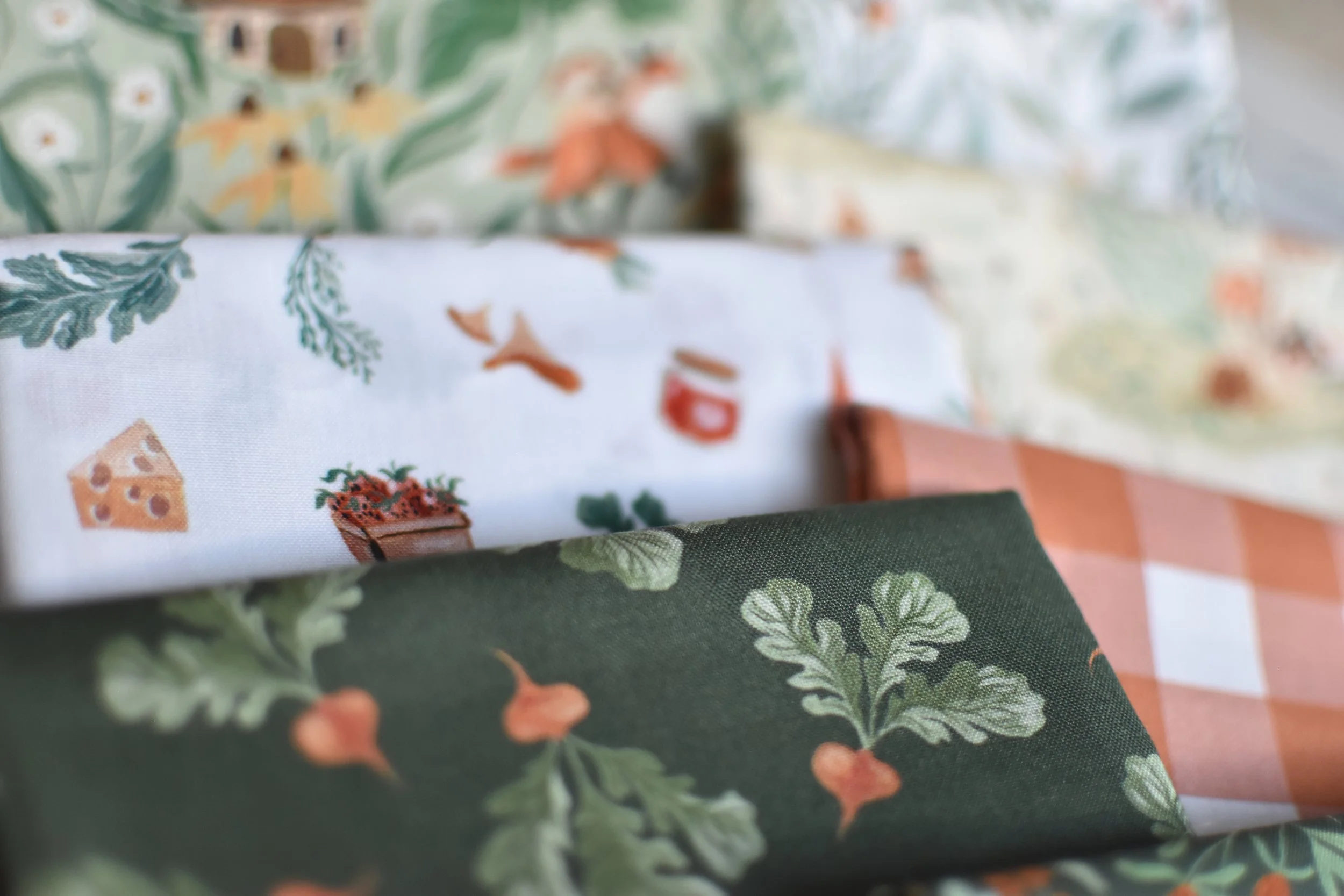 Close-up of fabric with vegetable and herb patterns, including carrots, herbs, and cheese illustrations.