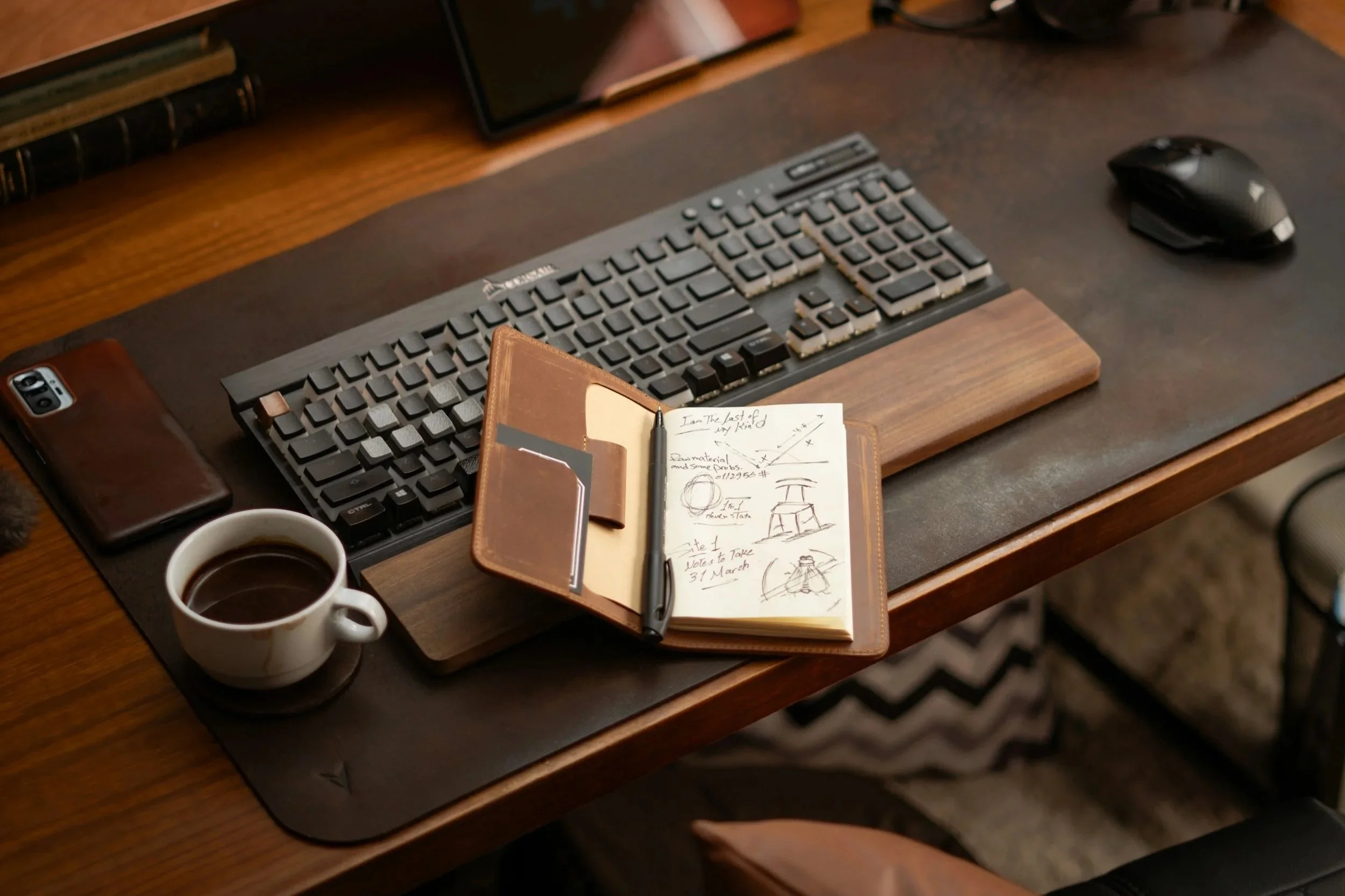 Open notebook with sketches and ideas on a desk with coffee and a keyboard, symbolizing the creative process of worldbuilding.