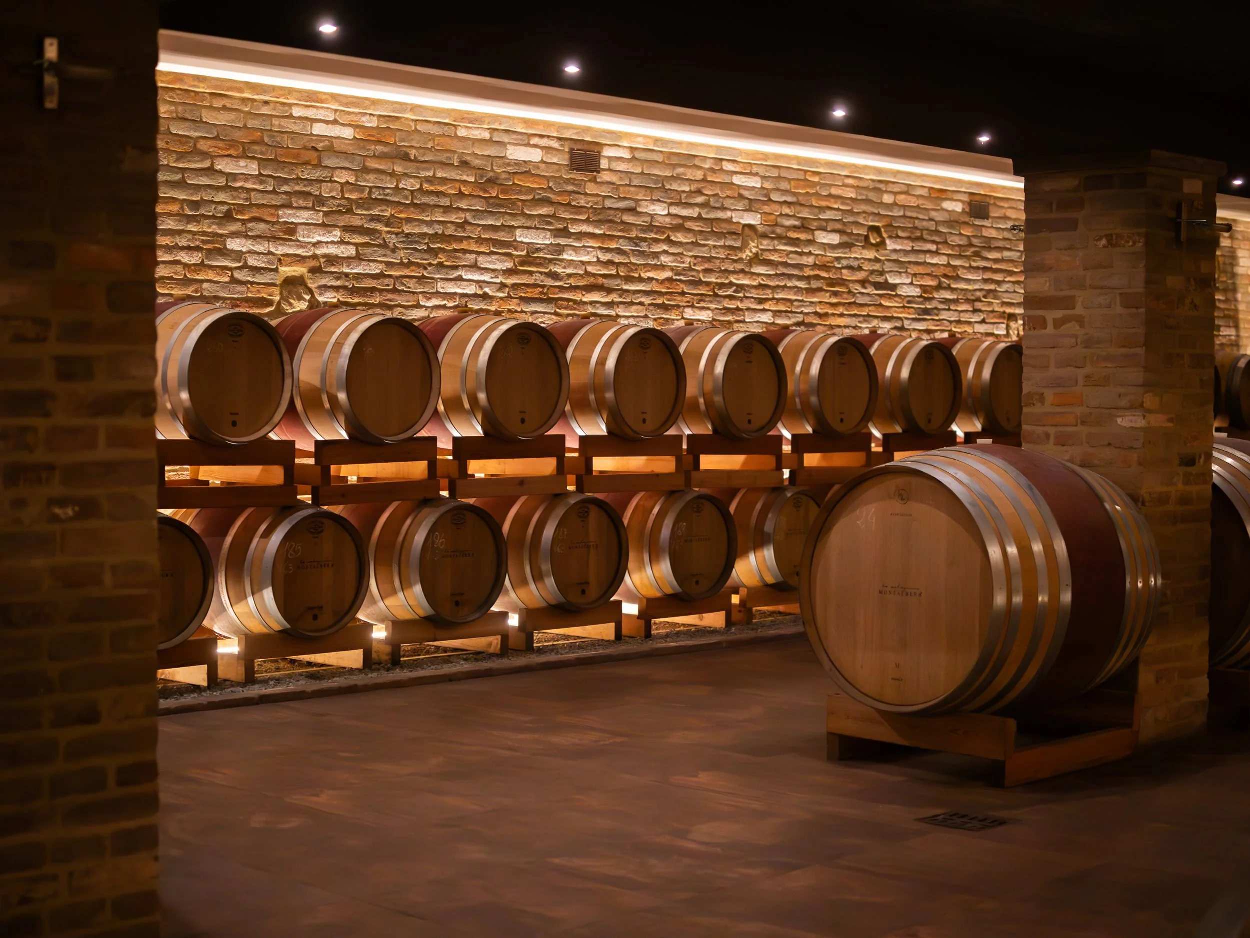 A European-style building with a tower, tiled roof, and painted white walls, surrounded by potted plants and outdoor seating.