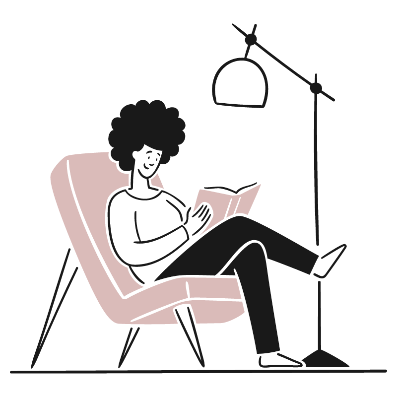 Person with curly hair sitting in a lounge chair reading a book at night, illuminated by a floor lamp.