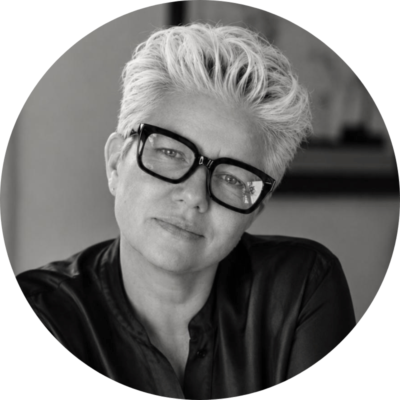 Black-and-white portrait of Dr Tanya Petersen with short, light-colored hair, wearing large black glasses and a dark top, looking at the camera with a slight smile.