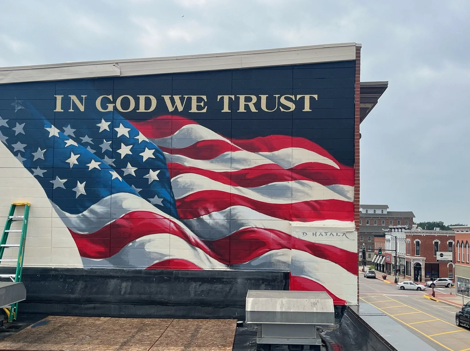 Mural of American flag with folded design and the words "In God We Trust" painted above in gold letters
