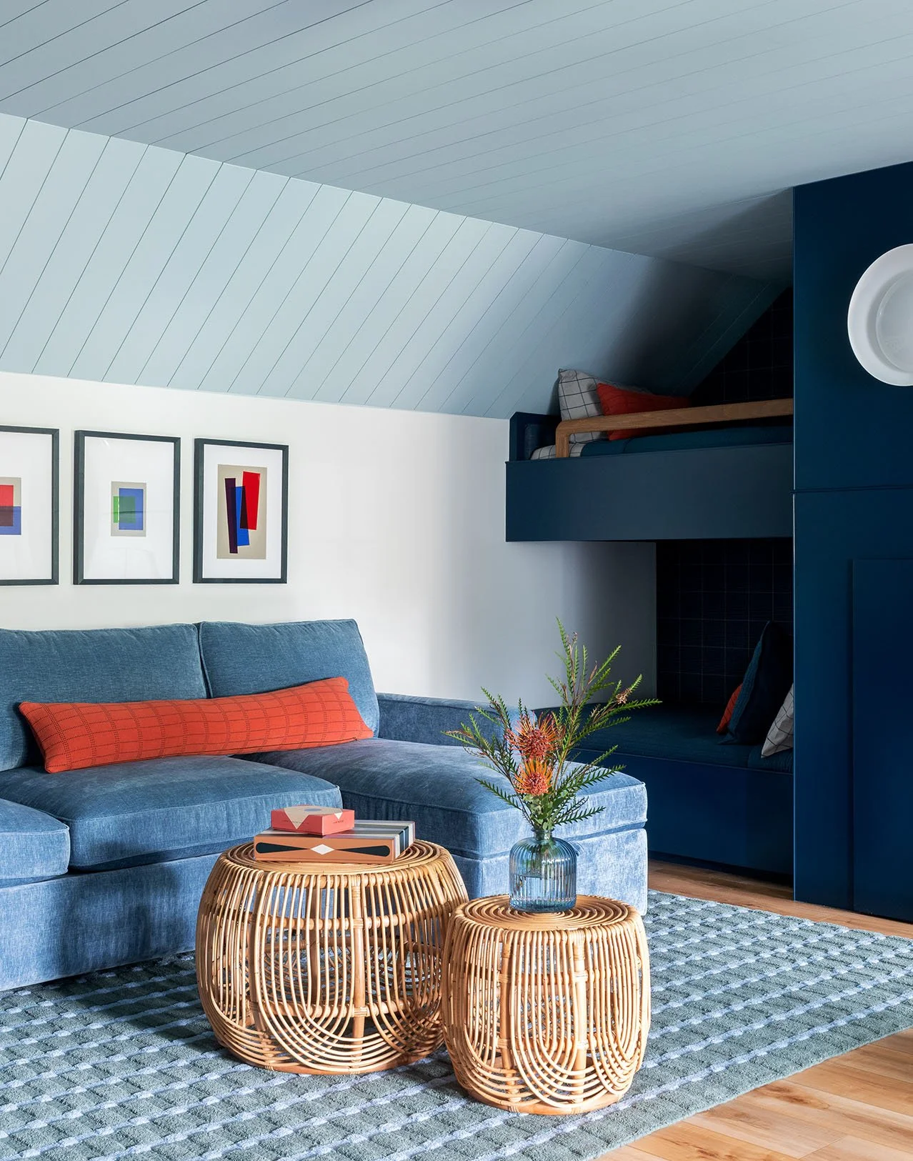 Blue couch with orange pillow and nested rattan tables