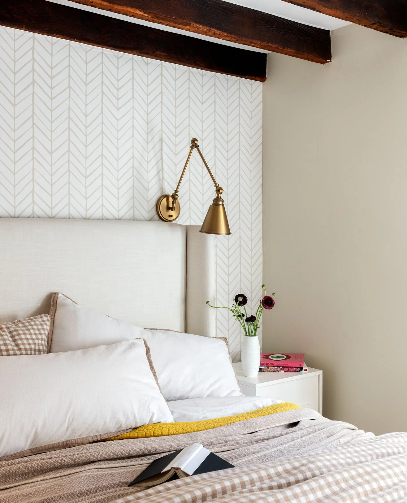 Brass reading light with flower vase next to cozy bed