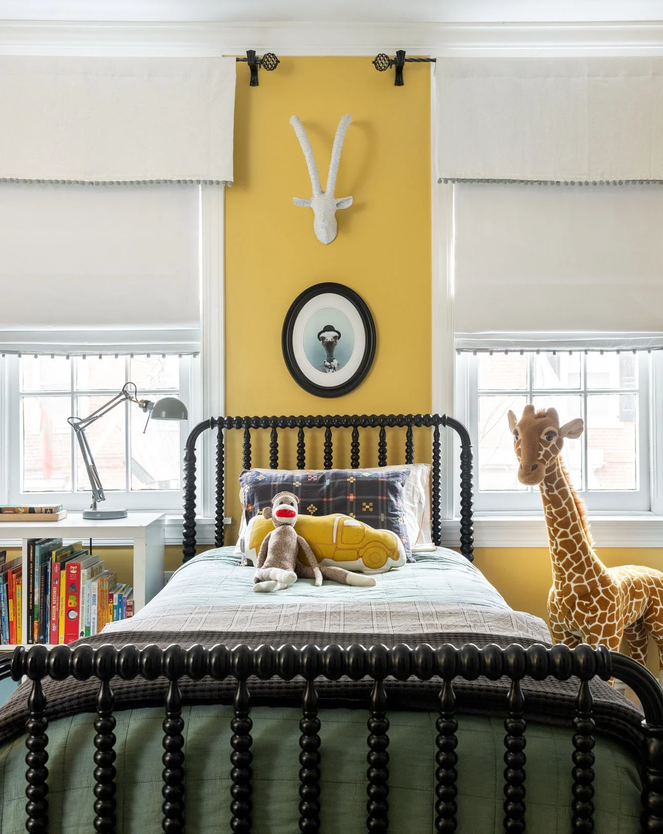 Twin black bed with green bedspread against yellow accent wall