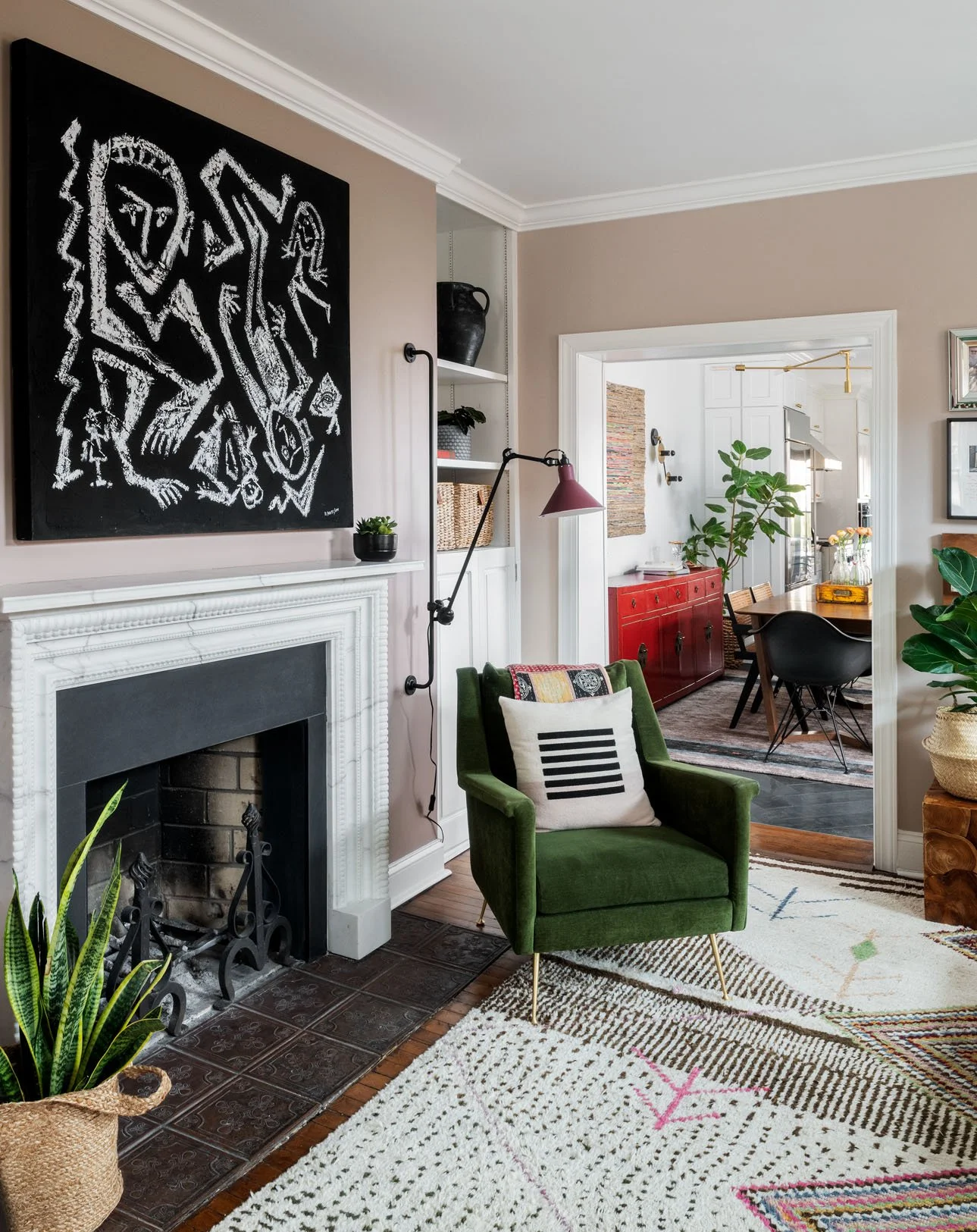 Green chair in living room with black and white art above the fireplace