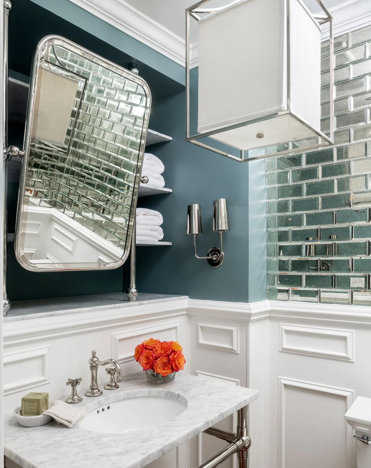 Jewel-toned power room with orange flowers in a vase on the counter