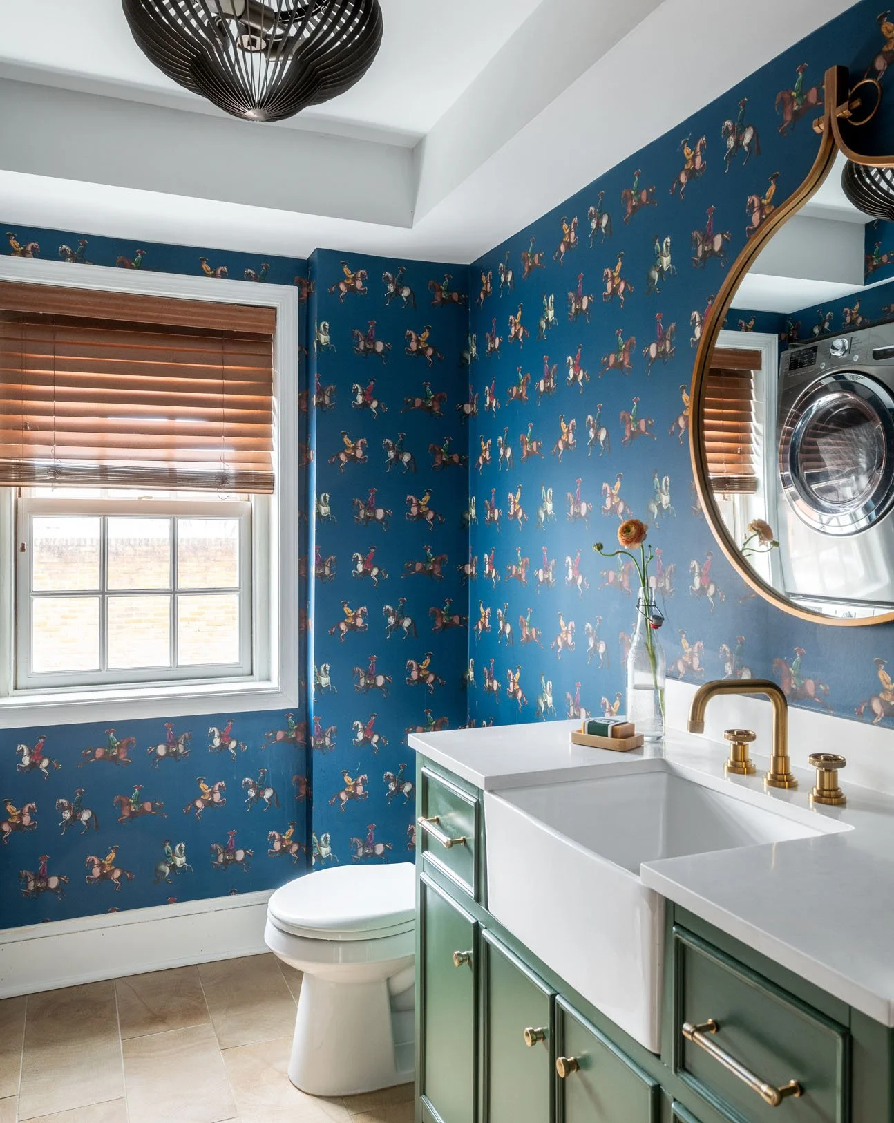 Blue horse wallpaper in a bathroom with white sink and green cabinets