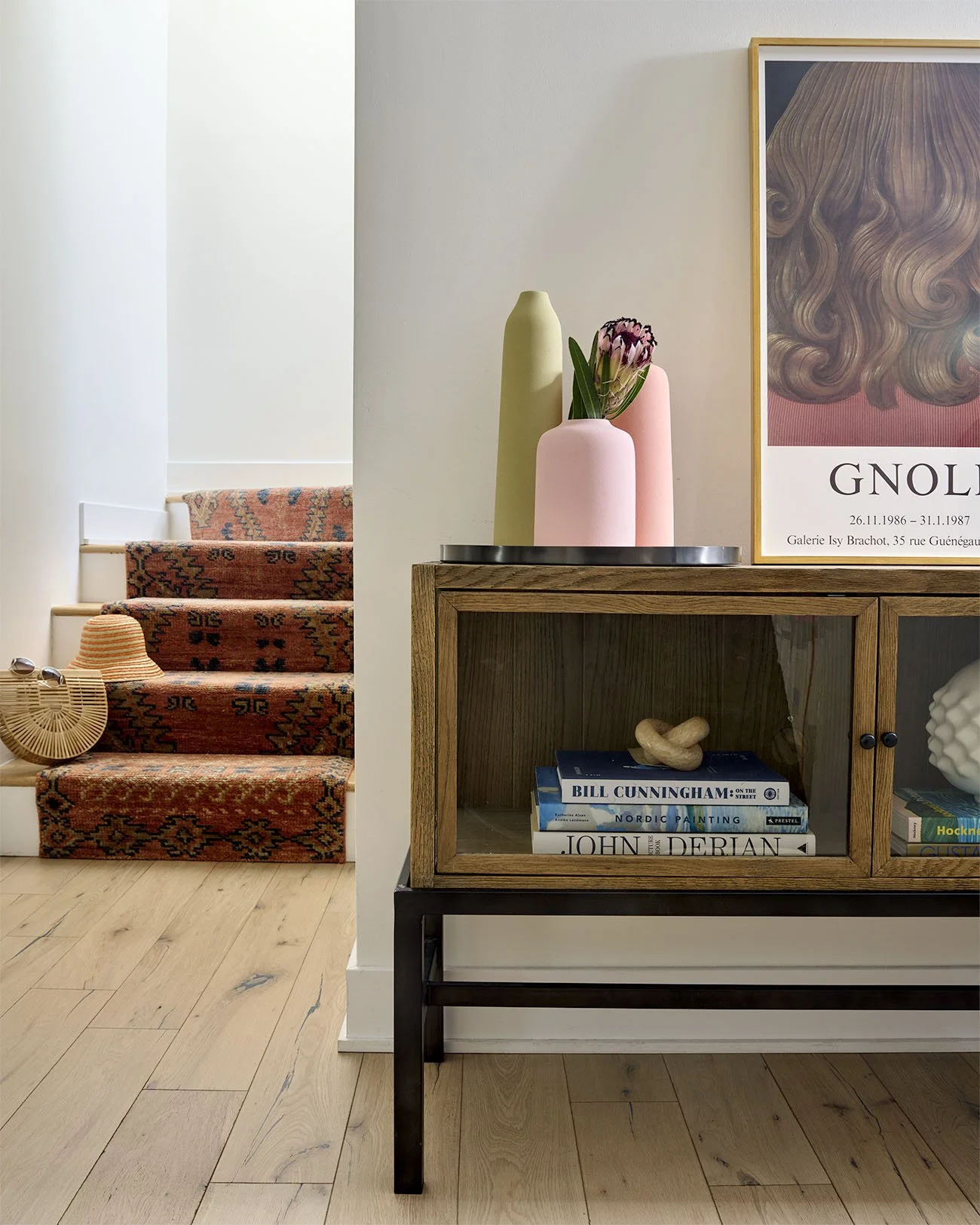 Carpeted stairs with a hat and basket with table with vases